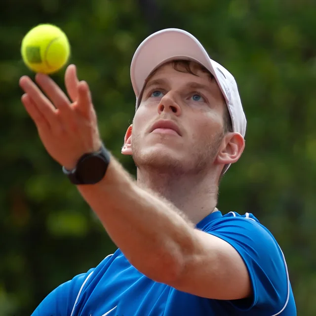 Timo gooit de tennisbal op voor een service